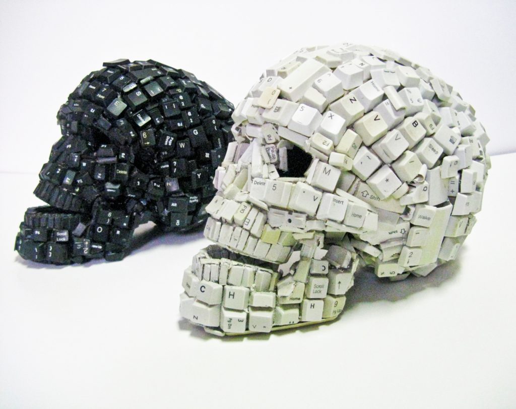 computer keyboard, black and white skull sculptures by Maurice Mbikayi